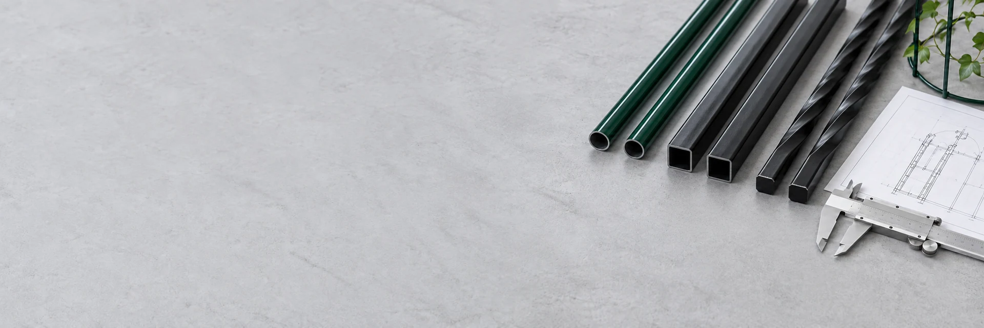 Illustrative plastic-coated steel tubes, twisted bars and square tubes on a development workbench